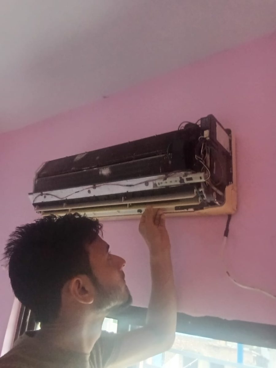 Sulaiman Sekh servicing a wall-mounted split AC indoor unit with the front panel removed